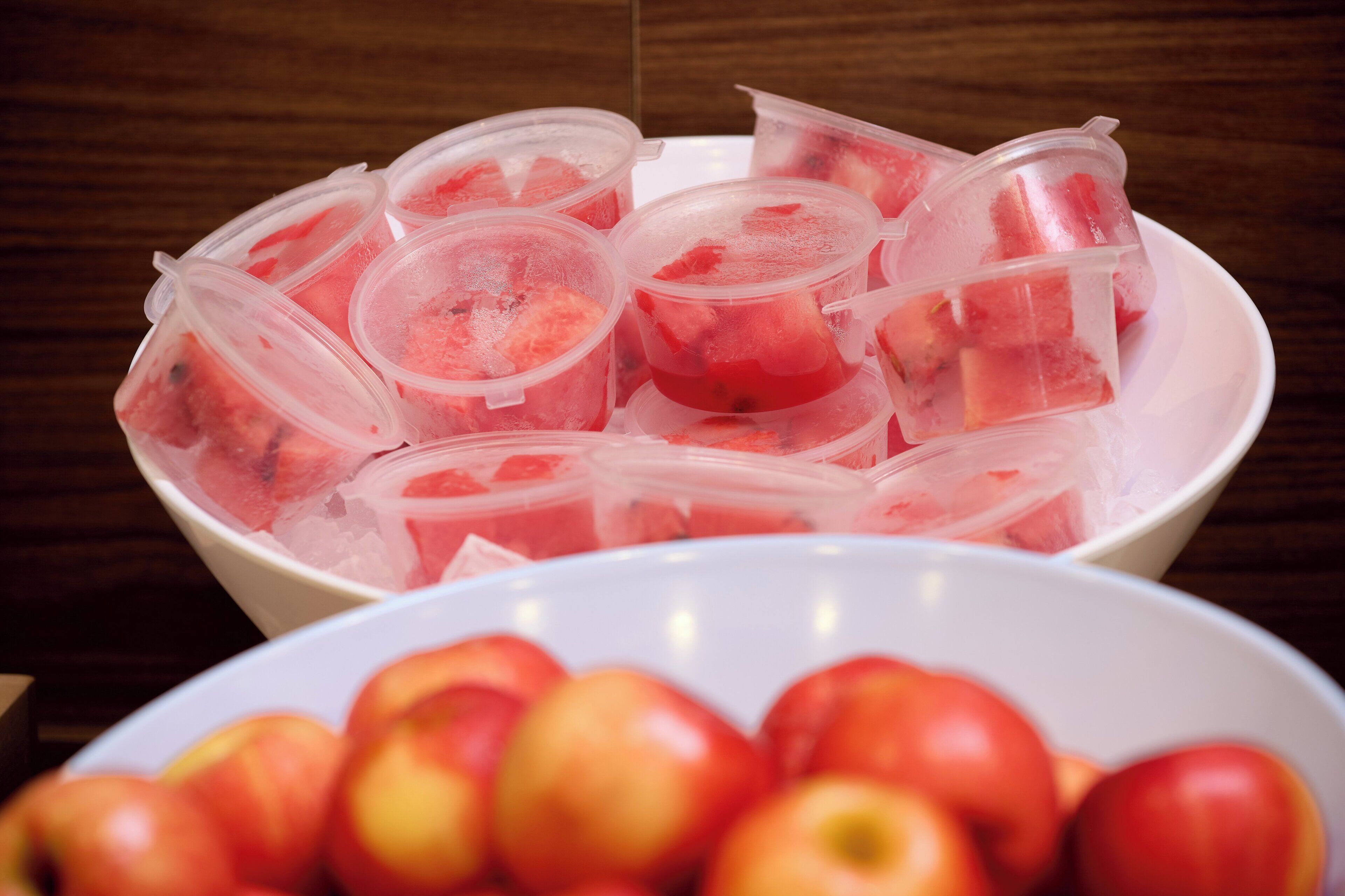 A bowl of watermelons in plastic containers on a table.