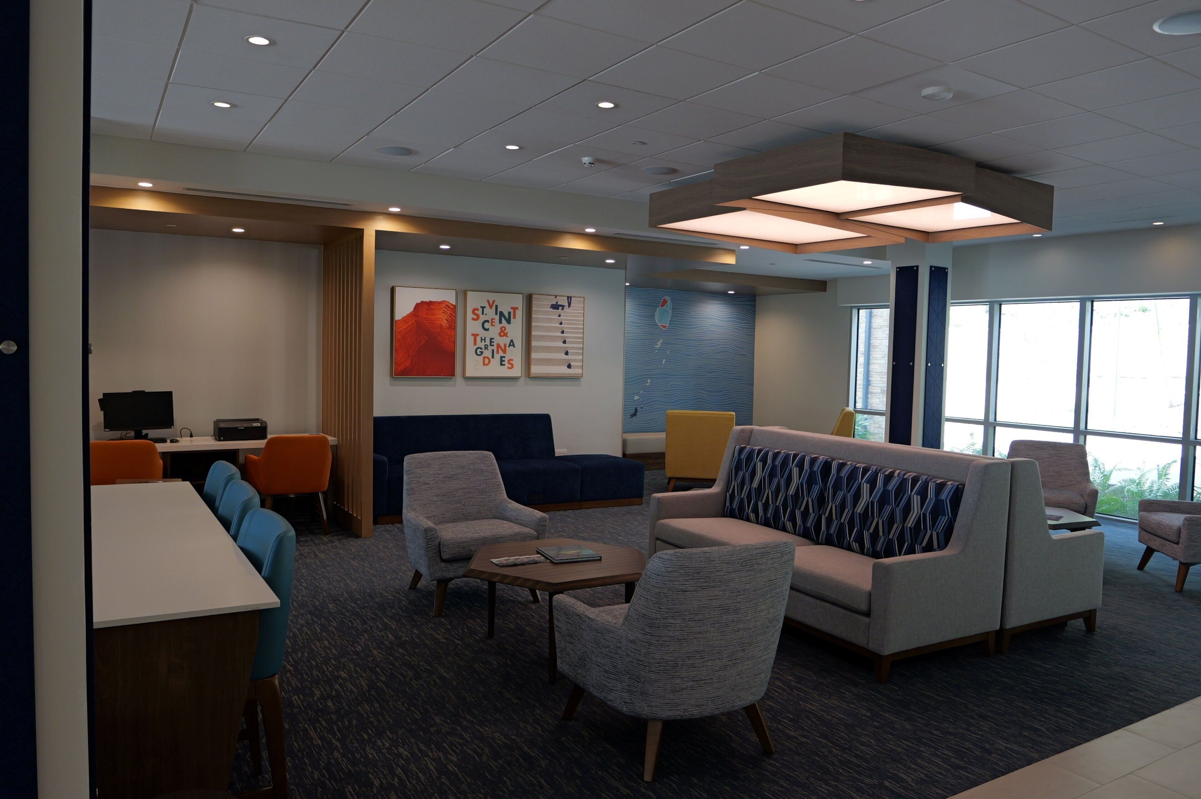 A modern hotel lobby with a reception desk, seating area, and large windows.
