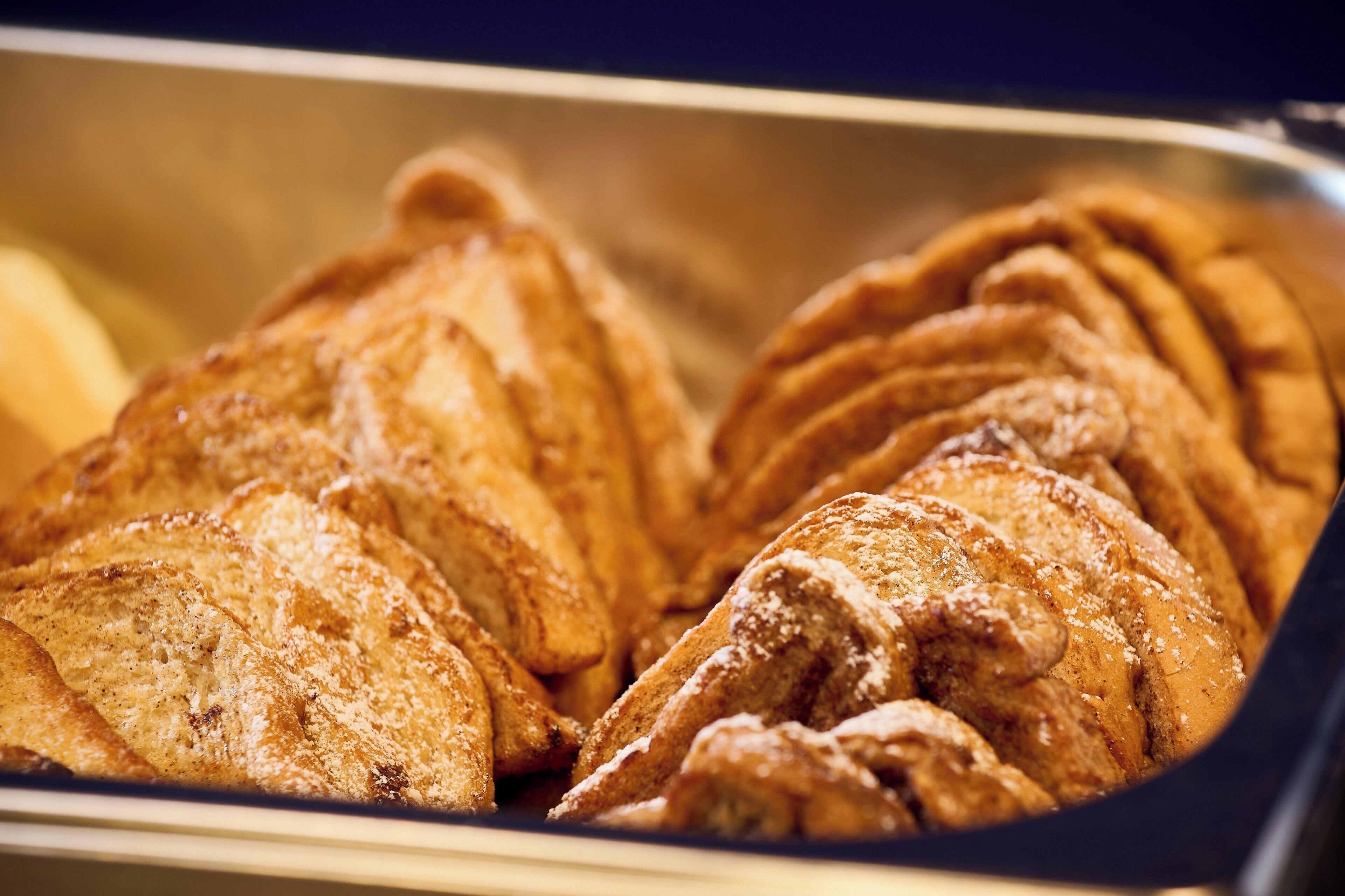 Un plateau de viennoiseries, probablement des croissants, saupoudrés de sucre glace.