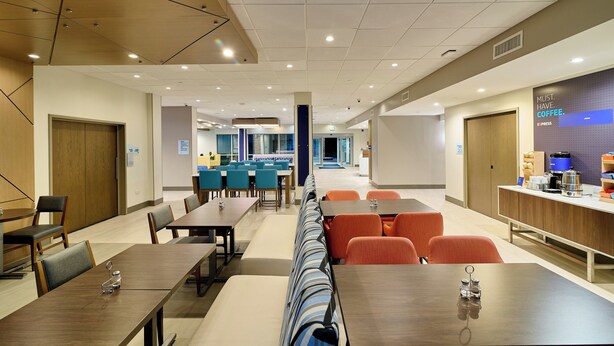 A modern hotel lobby with multiple seating areas, including tables and chairs, and a coffee station. - Holiday Inn Express & Suites St. Vincent - Grenadines by IHG (Diamond)