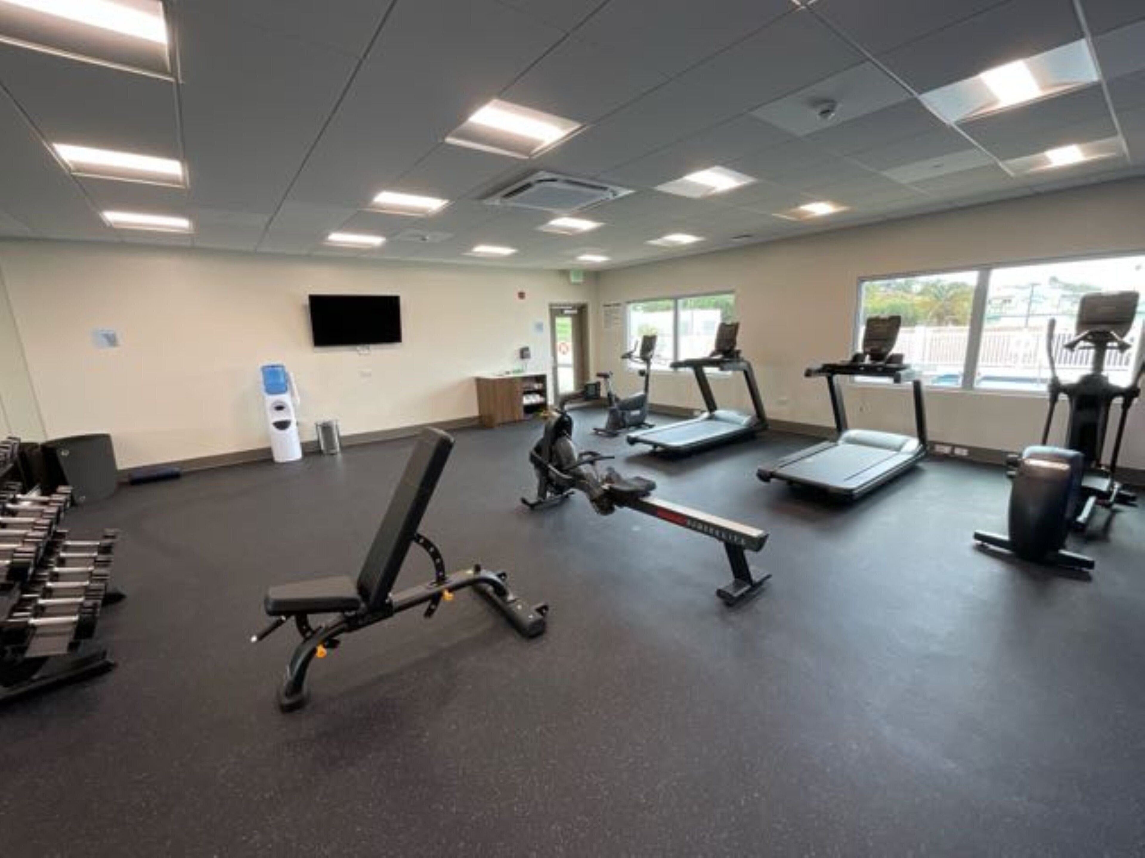 A gym with treadmills, weight benches, and dumbbells.