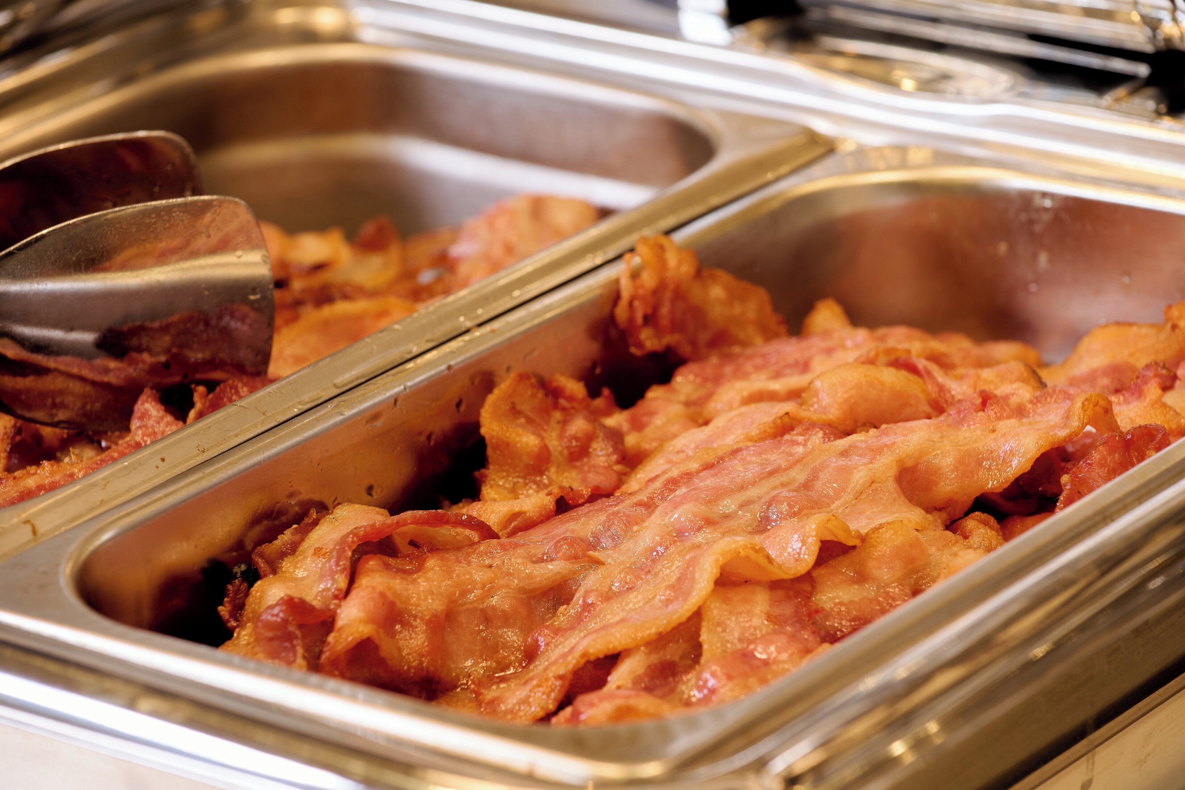 Un buffet con diversi vassoi di pancetta.