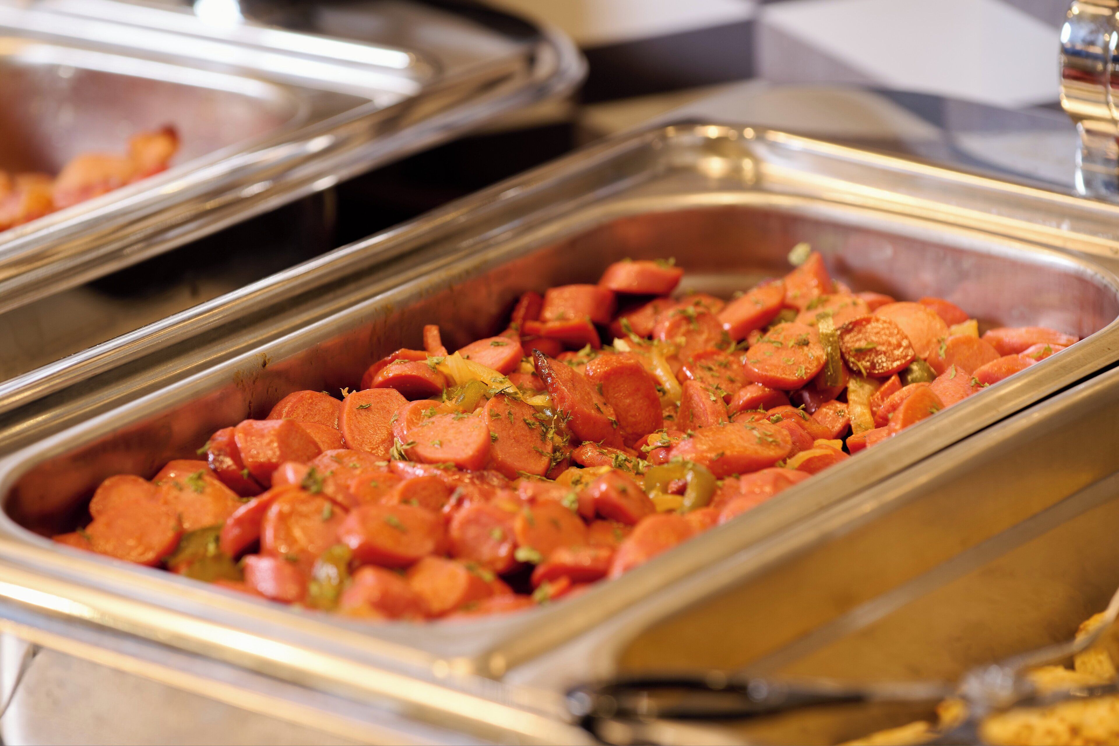 Un bufé con diversos alimentos, entre ellos salchichas en rodajas y verduras.