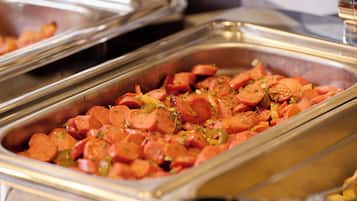 Un bufé con diversos alimentos, entre ellos salchichas en rodajas y verduras.