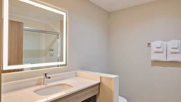 A modern bathroom with a large mirror, a sink, and a toilet.