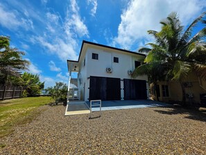 A two-story house with a covered driveway, a staircase, and a sign indicating a parking area.
