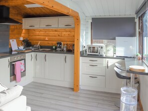 Una cocina moderna con armarios blancos, techo de madera y ventana con vistas.