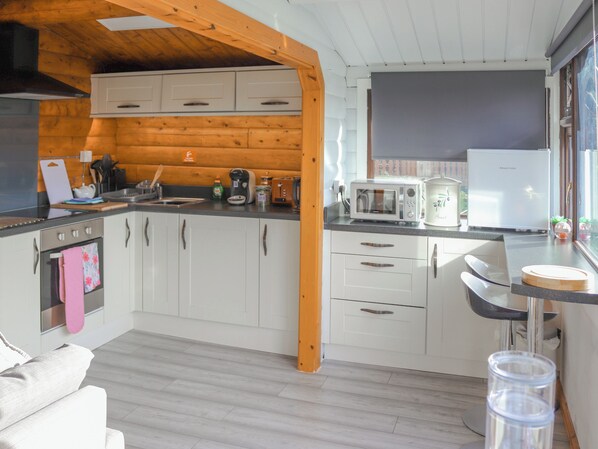 A modern kitchen with white cabinets, a wooden ceiling, and a window with a view.