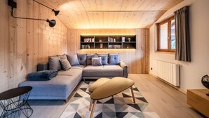 A cozy room with a wooden ceiling, a sectional sofa, a small table, and a bookshelf. - 1st floor, view village, balcony, fireplace or stove, parking, tv, ski locker, 97m², Morzine (Morzine)
