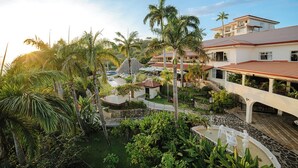 A resort with multiple buildings, palm trees, and a central courtyard with a fountain. - Vista Suites at Parador (Quepos)