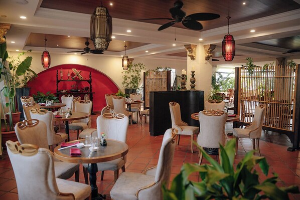 A restaurant with round tables, white chairs, and hanging red lanterns.