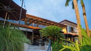 A hotel with outdoor seating, a staircase, and palm trees. - Vista Suites at Parador (Quepos)