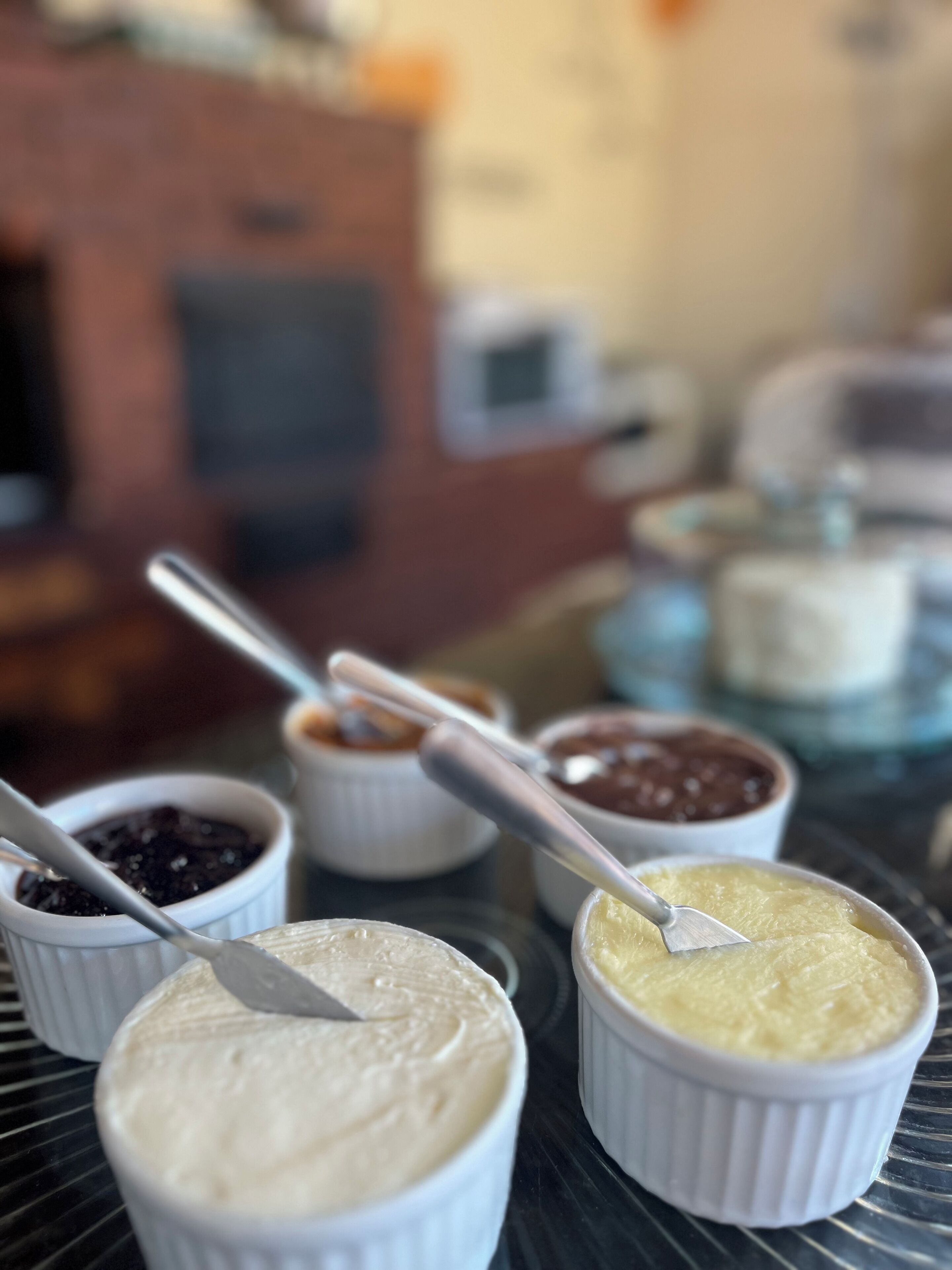 A close-up of various small bowls containing different food items, with spoons in them, on a table.