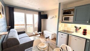 A compact living space with a sofa, dining table, chairs, a small kitchen area with a microwave and dishwasher, and a balcony with curtains. - 200m from resort center, 1st floor, balcony, tv, ski locker, 25m², Avoriaz (Avoriaz)