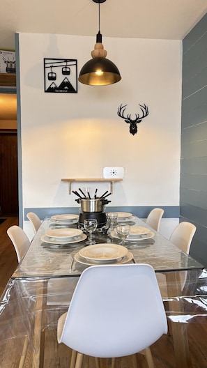 A dining area with a glass table, white chairs, a black lamp, and a deer head decoration on the wall. - 200m from resort center, 1st floor, balcony, tv, ski locker, 25m², Avoriaz (Avoriaz)