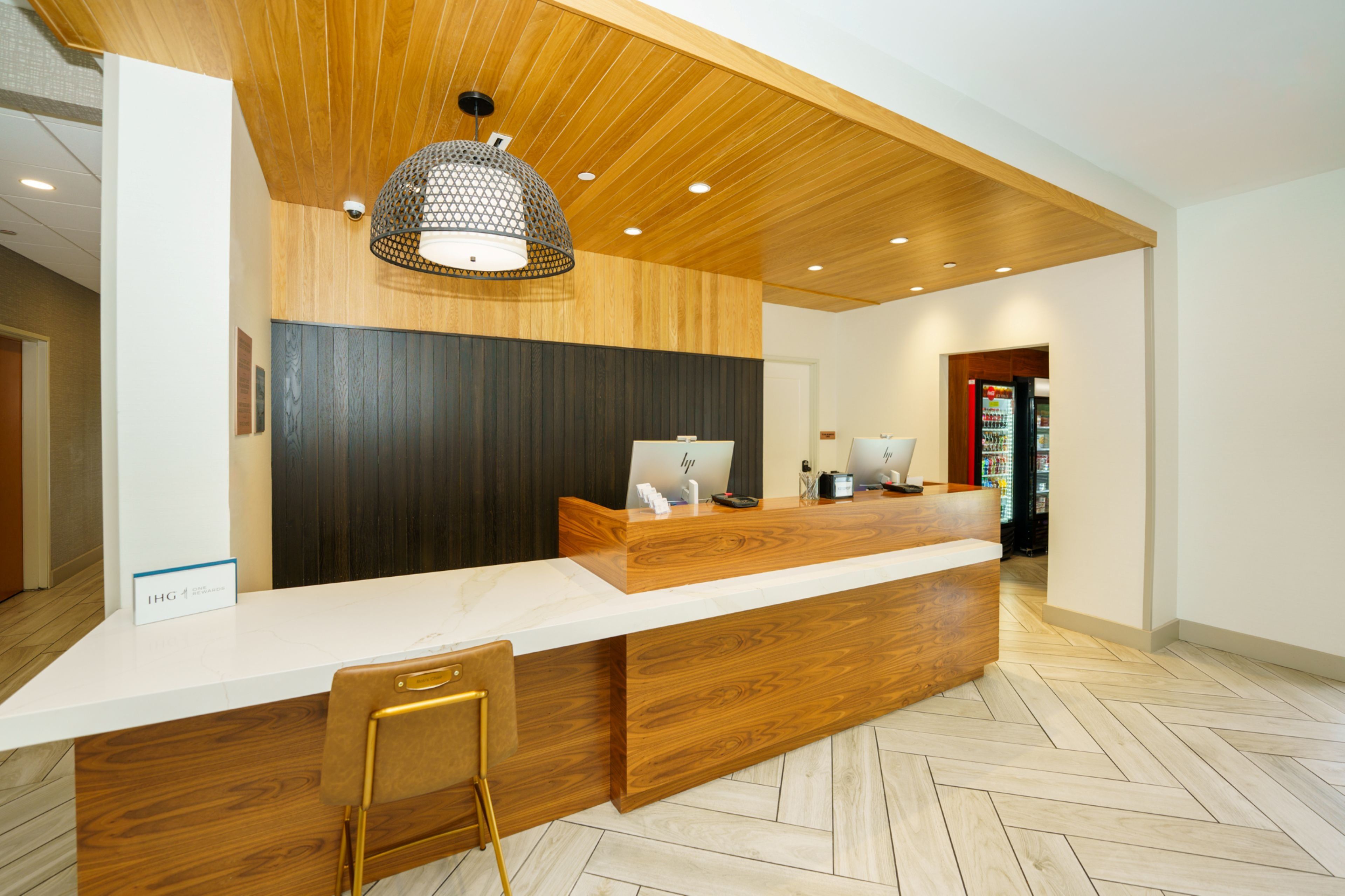 A reception desk with a wooden finish, a white counter, and a modern pendant light.