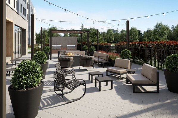 Un patio al aire libre con mobiliario moderno, una parrilla y luces colgantes.