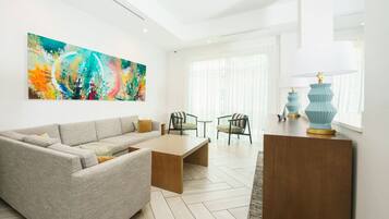 A modern living room with a grey sofa, a wooden coffee table, and a colorful abstract painting on the wall.
