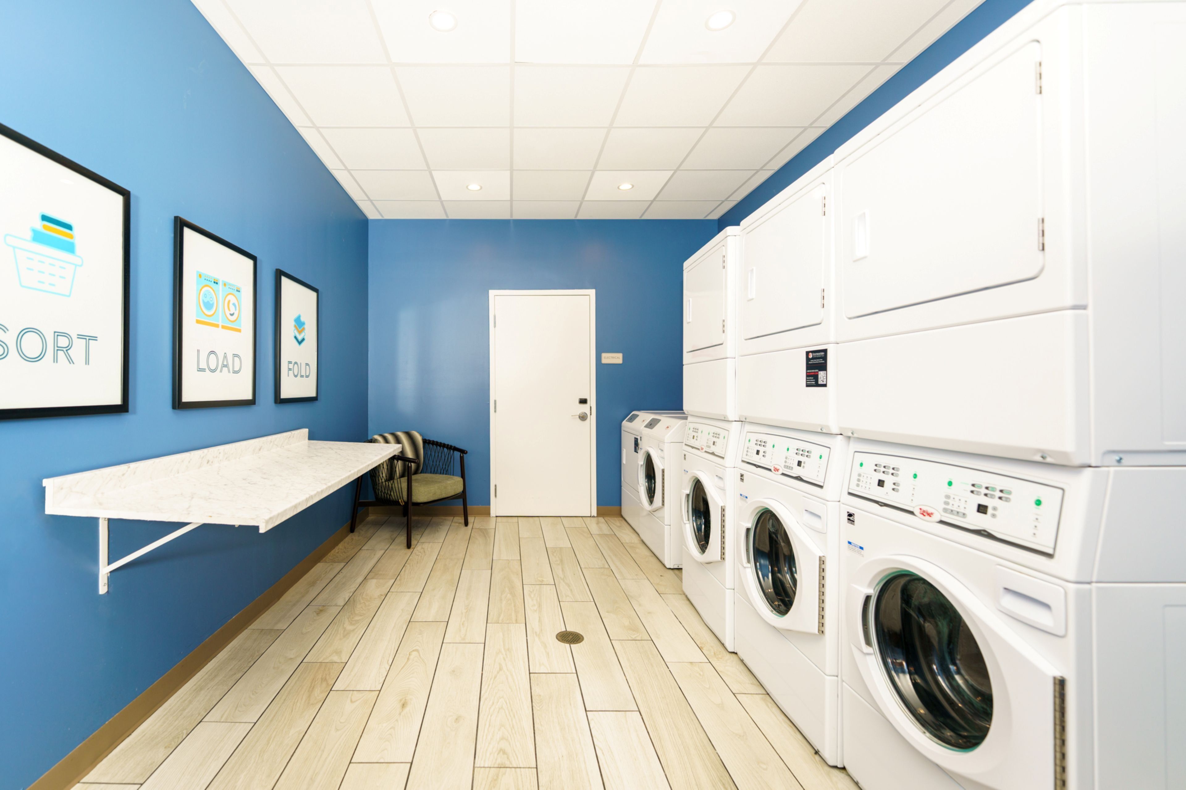 A laundry room with a blue wall, a white door, and a row of stacked washing machines.