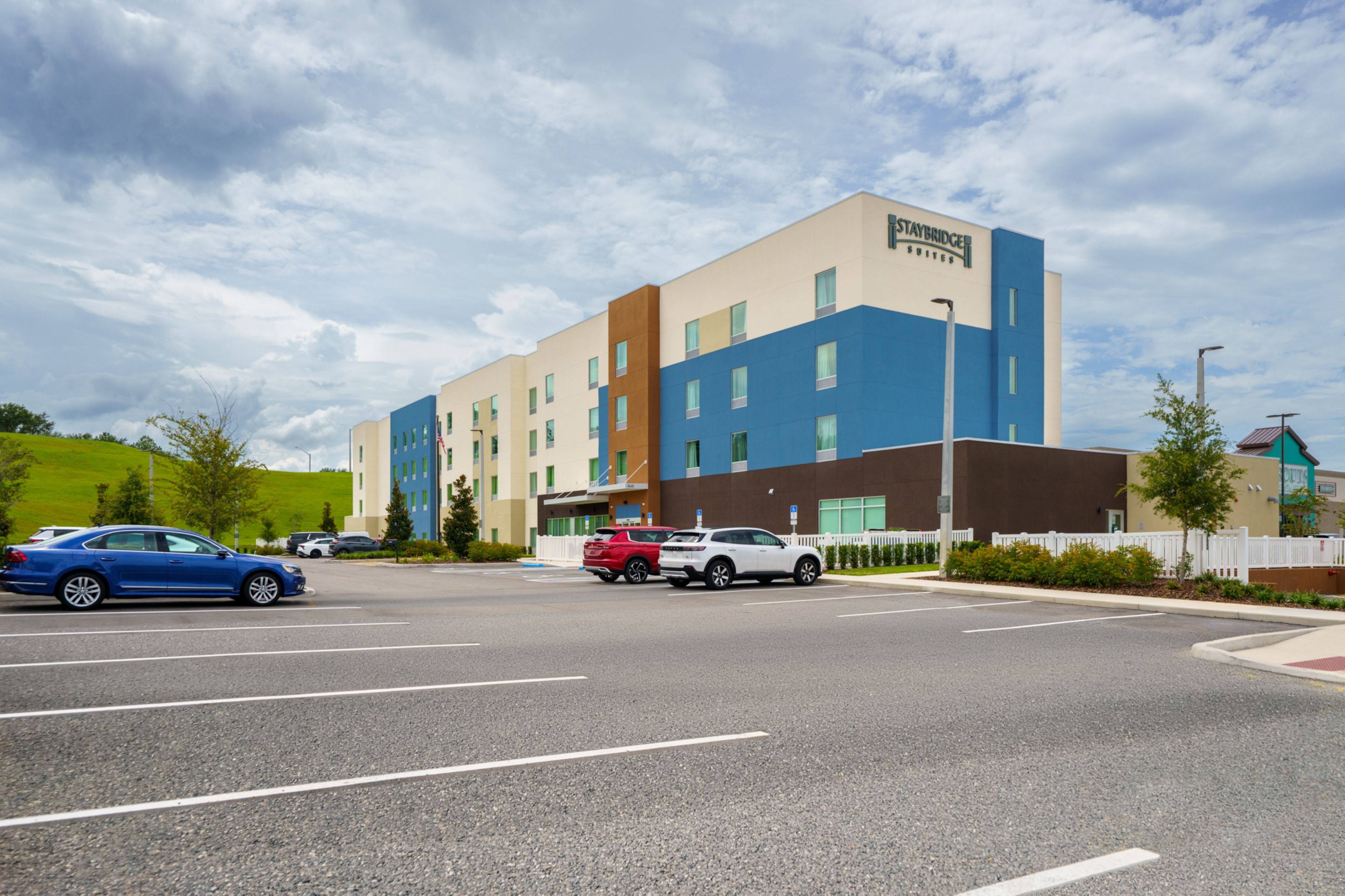 A Staybridge Suites hotel with a parking lot and a road in front.