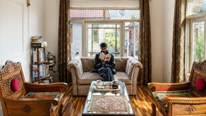A room with a sofa, two chairs, a coffee table, a bookshelf, and a window with curtains. - Shesh Bagh Boutique Homestay (Srinagar)