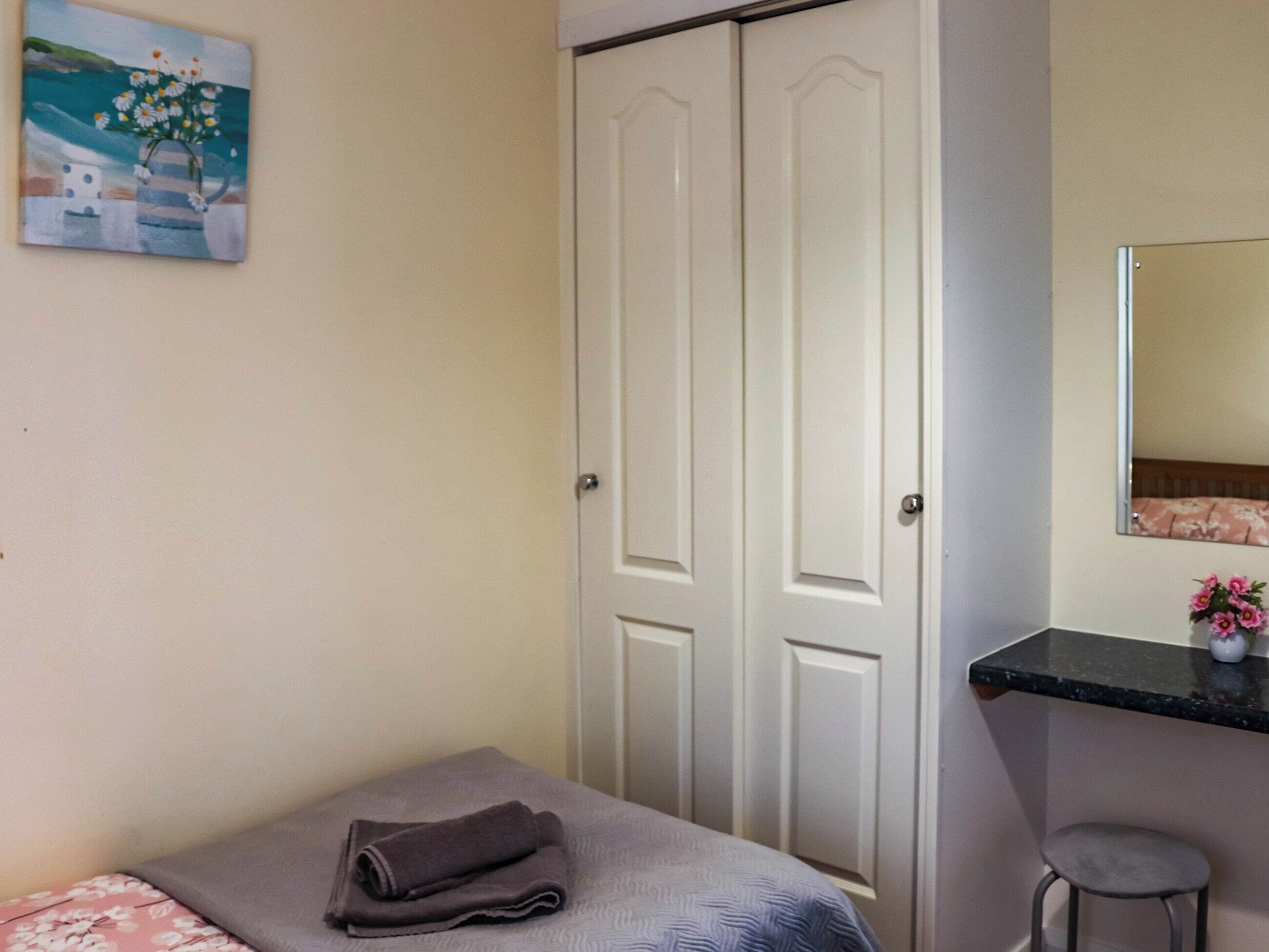 A bedroom with a bed, a nightstand, a mirror, and a wardrobe.
