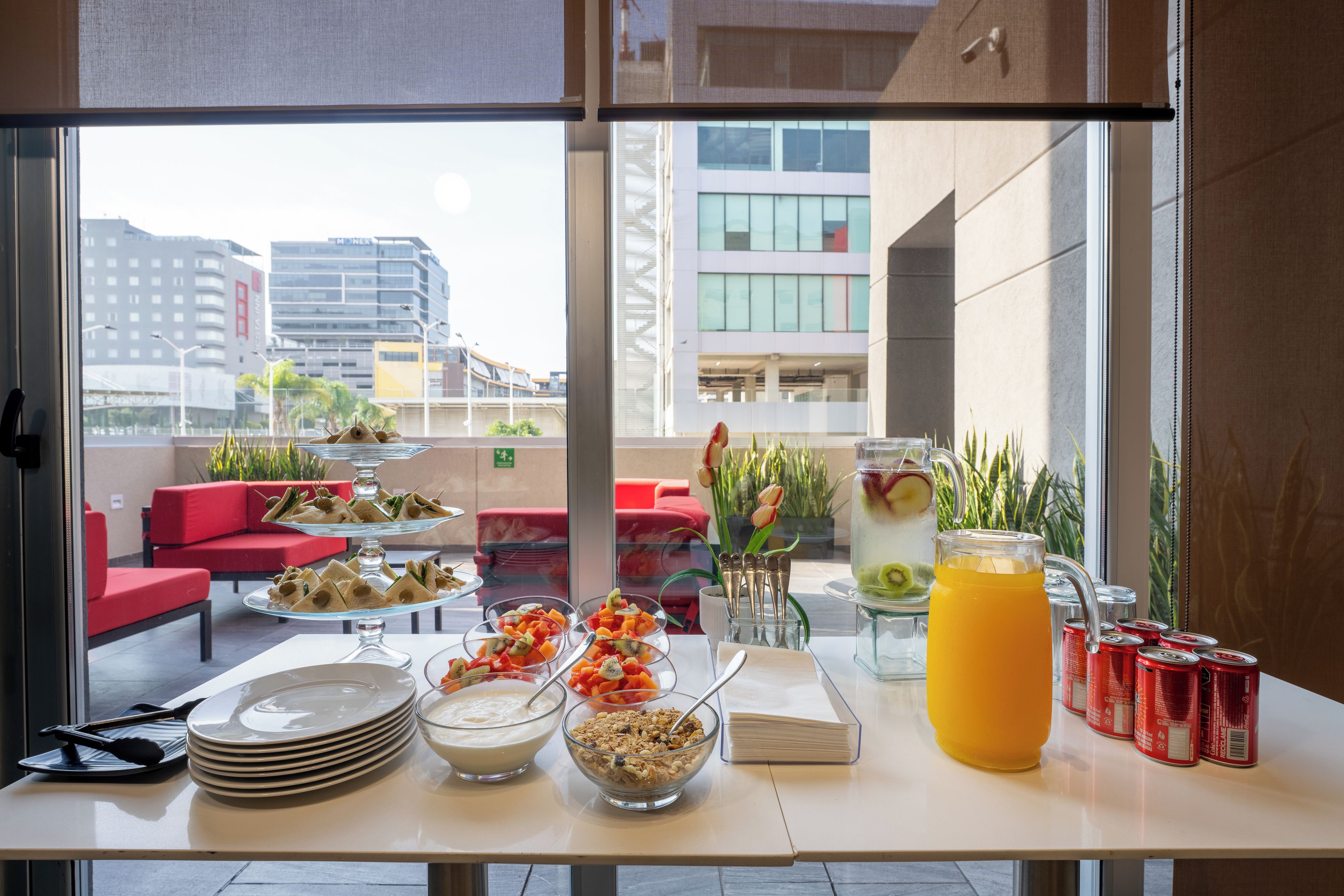 A breakfast buffet with plates, bowls, and a pitcher of orange juice.
