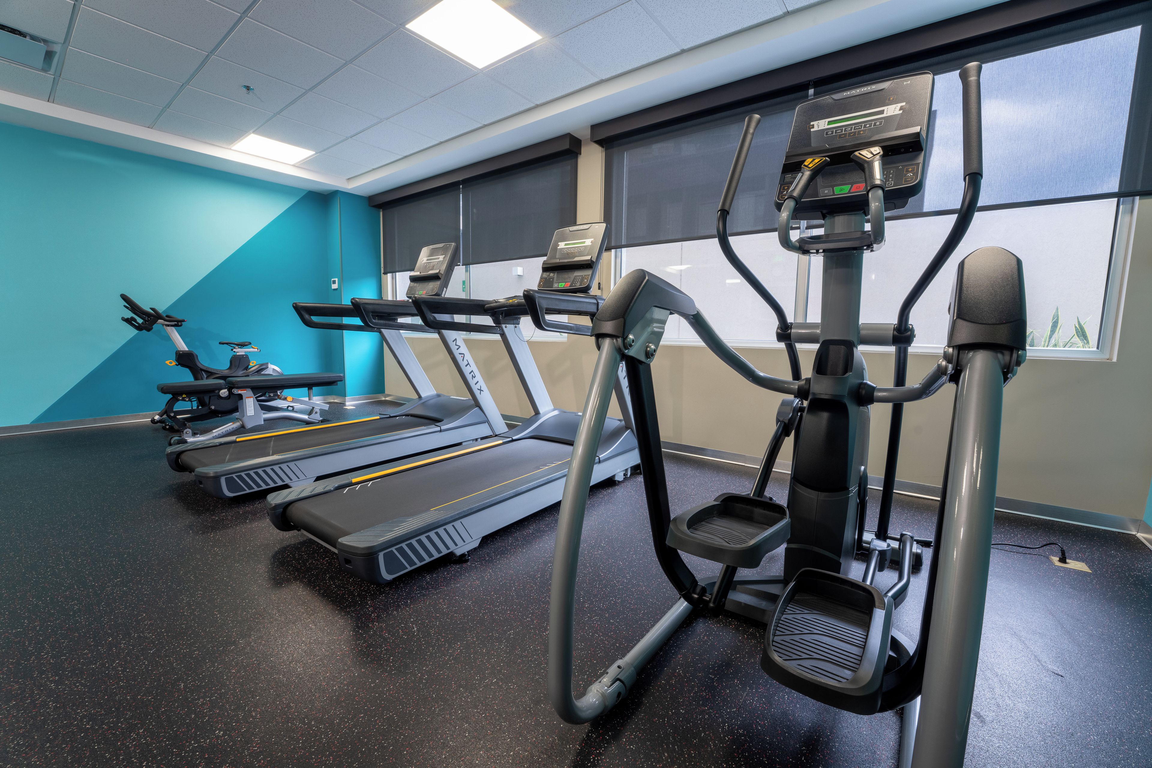 Une salle de sport équipée de tapis de course, de vélos elliptiques et d’un vélo d’appartement.