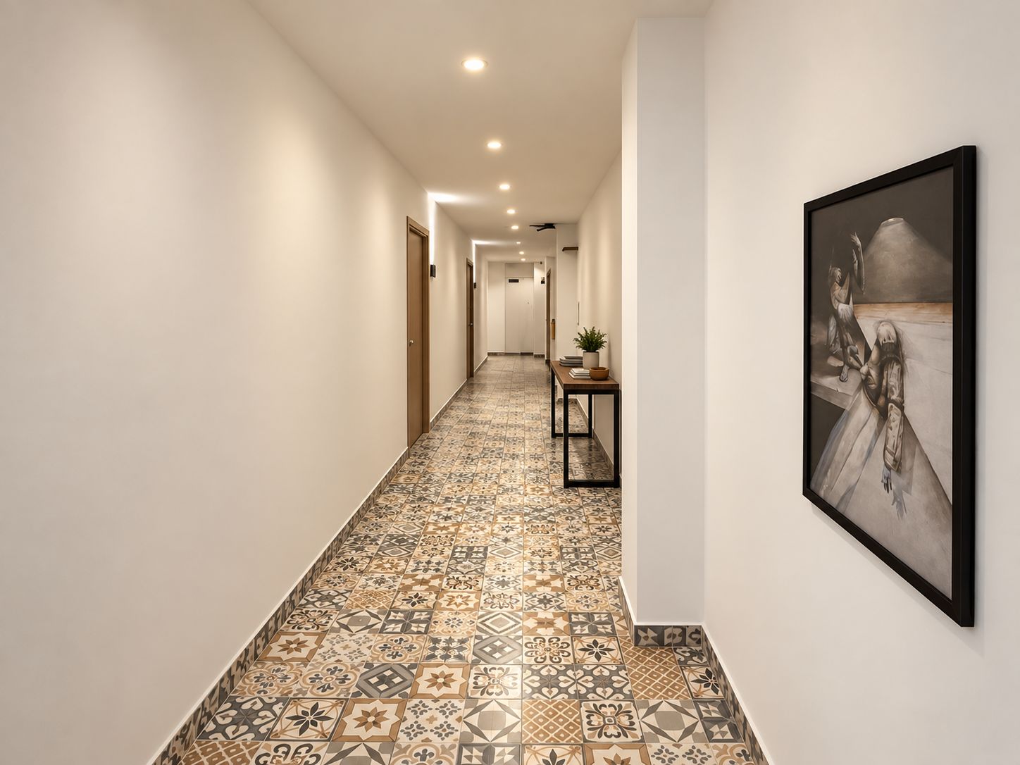 Un corridoio con piastrelle decorative, un quadro appeso al muro e un tavolo con una pianta e libri.