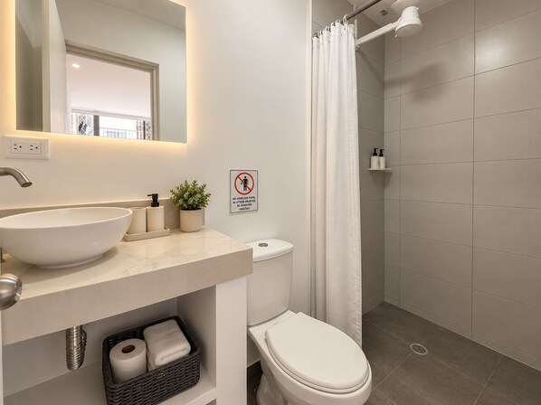 A modern bathroom with a large sink, toilet, and shower area.