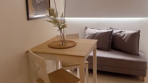 A minimalist living room with a wooden table, white chair, and a grey sofa. - Apartasuites ISABEL (Cali)