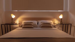 A neatly made bed with two pillows and two bedside tables with lamps. - Apartasuites ISABEL (Cali)