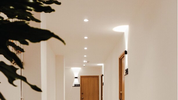 A hallway with patterned tile flooring, a wooden door labeled "205", and recessed ceiling lights. - Apartasuites ISABEL (Cali)