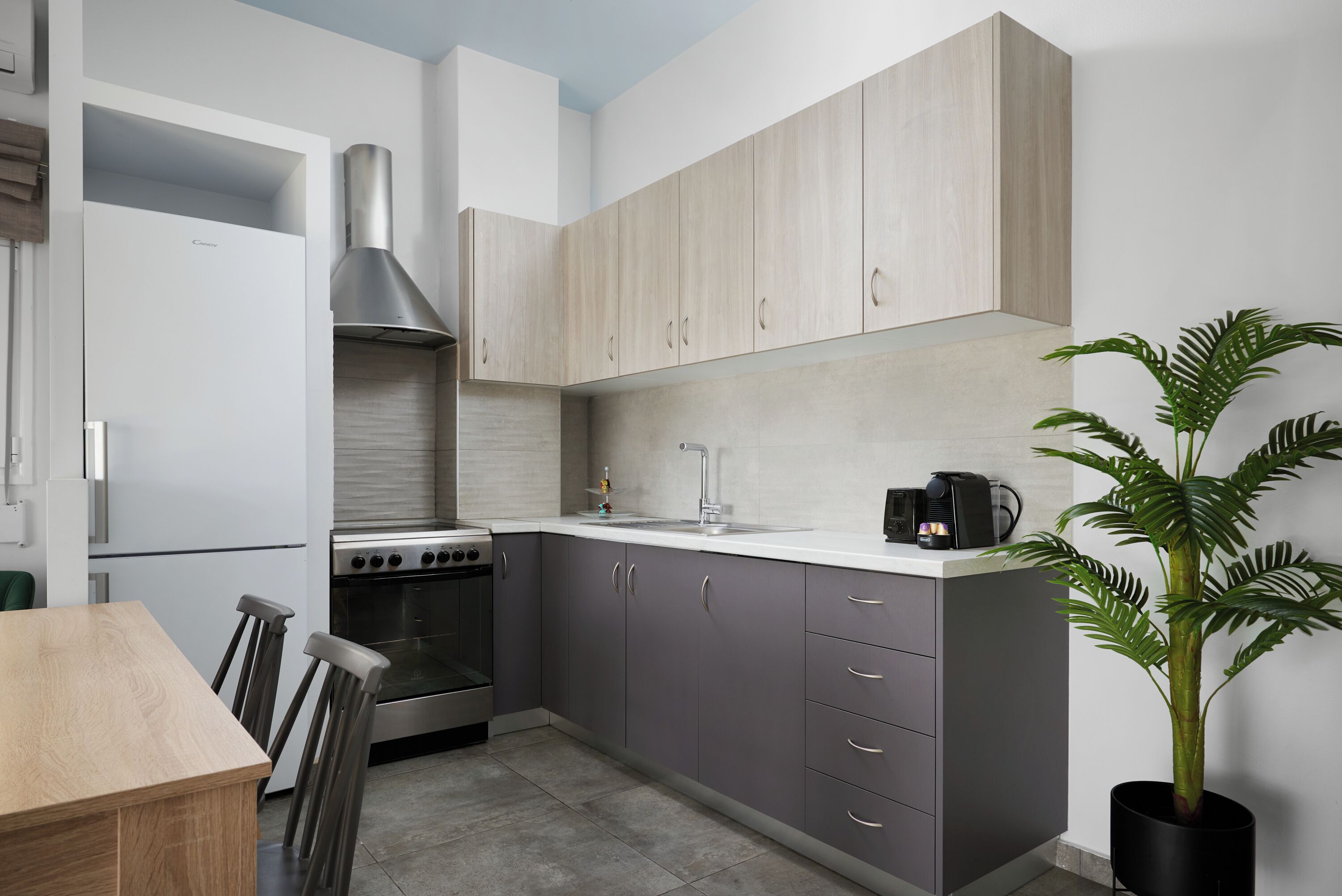 Een moderne keuken met grijze kastjes, een roestvrijstalen afzuigkap en een koffieapparaat.