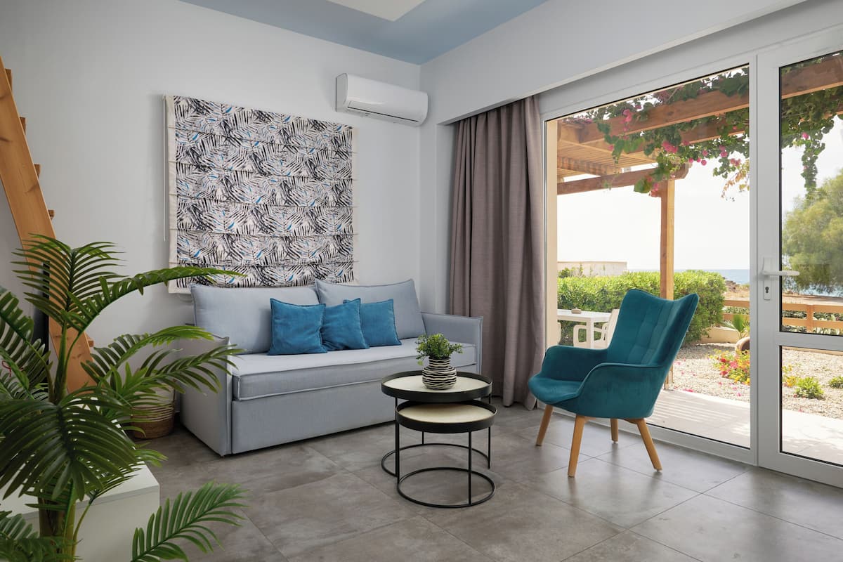 Un salon moderne avec un canapé gris, des coussins bleus, une table basse ronde ornée d’une plante et un fauteuil bleu.