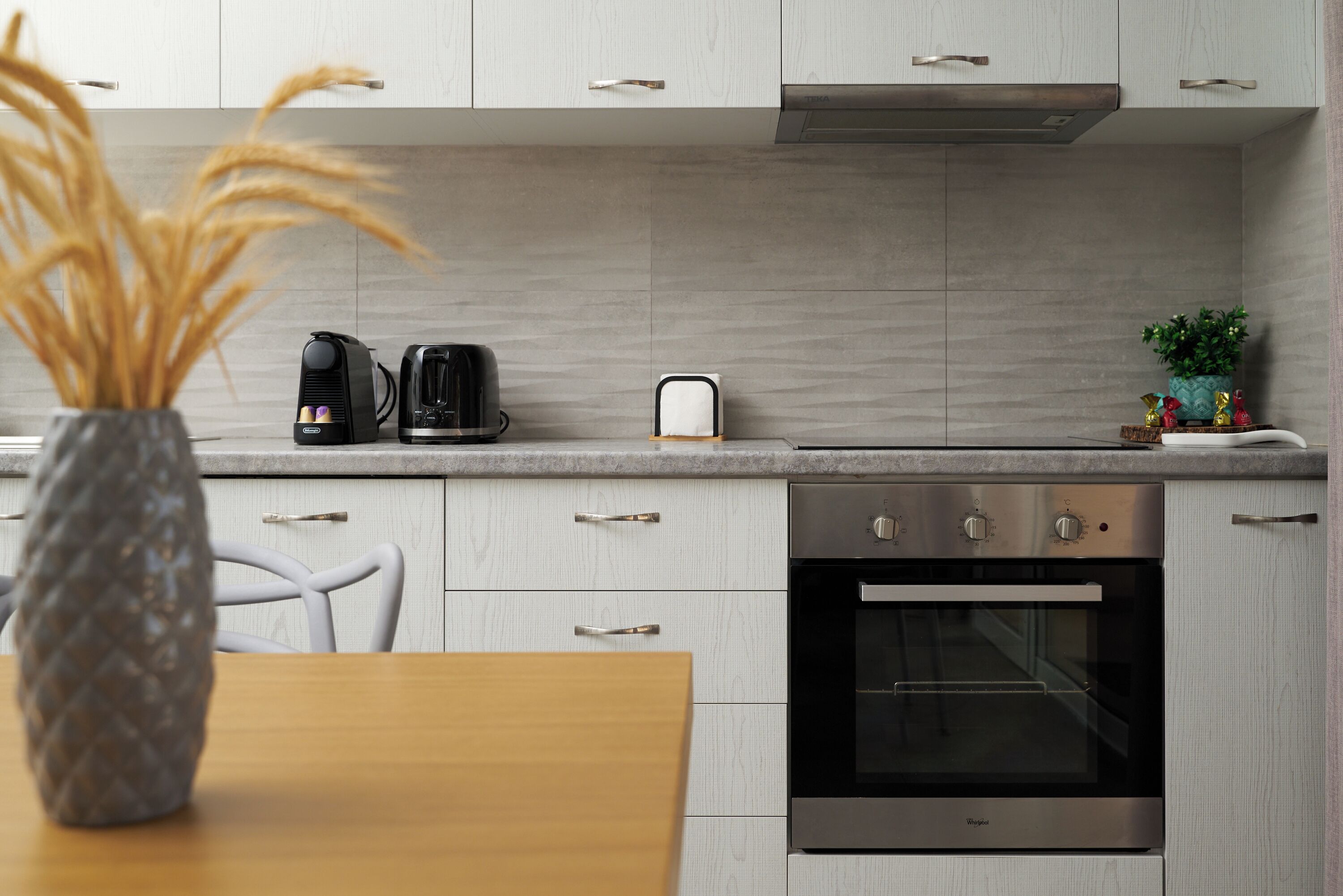 Una cocina moderna con horno empotrado, cafetera y tostadora sobre la encimera.