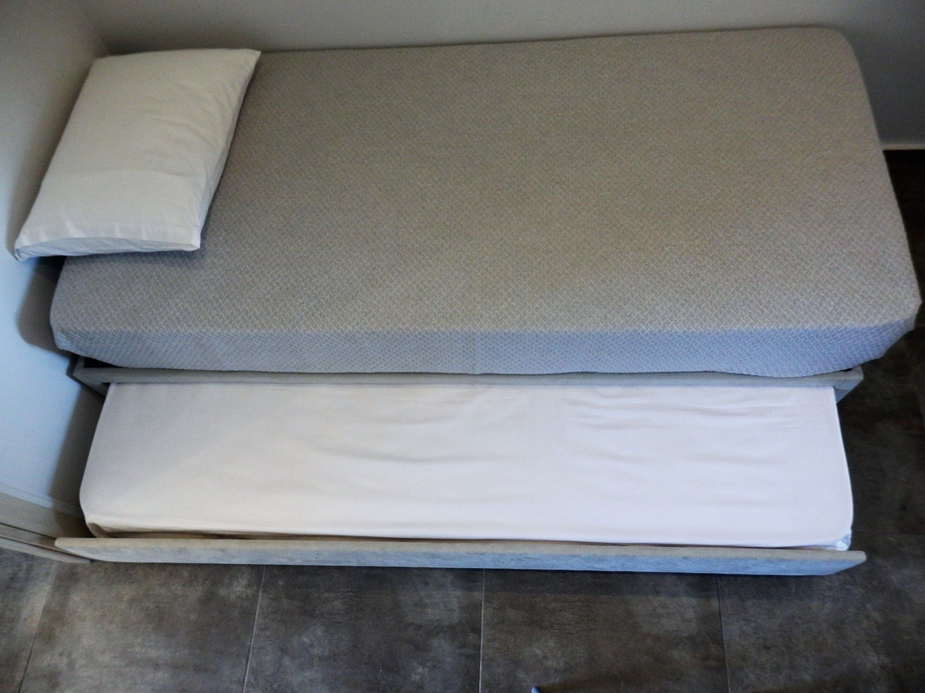 A bed with three mattresses of different thicknesses.
