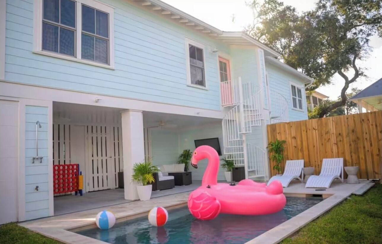 A backyard with a swimming pool, a pink flamingo float, and a wooden fence.