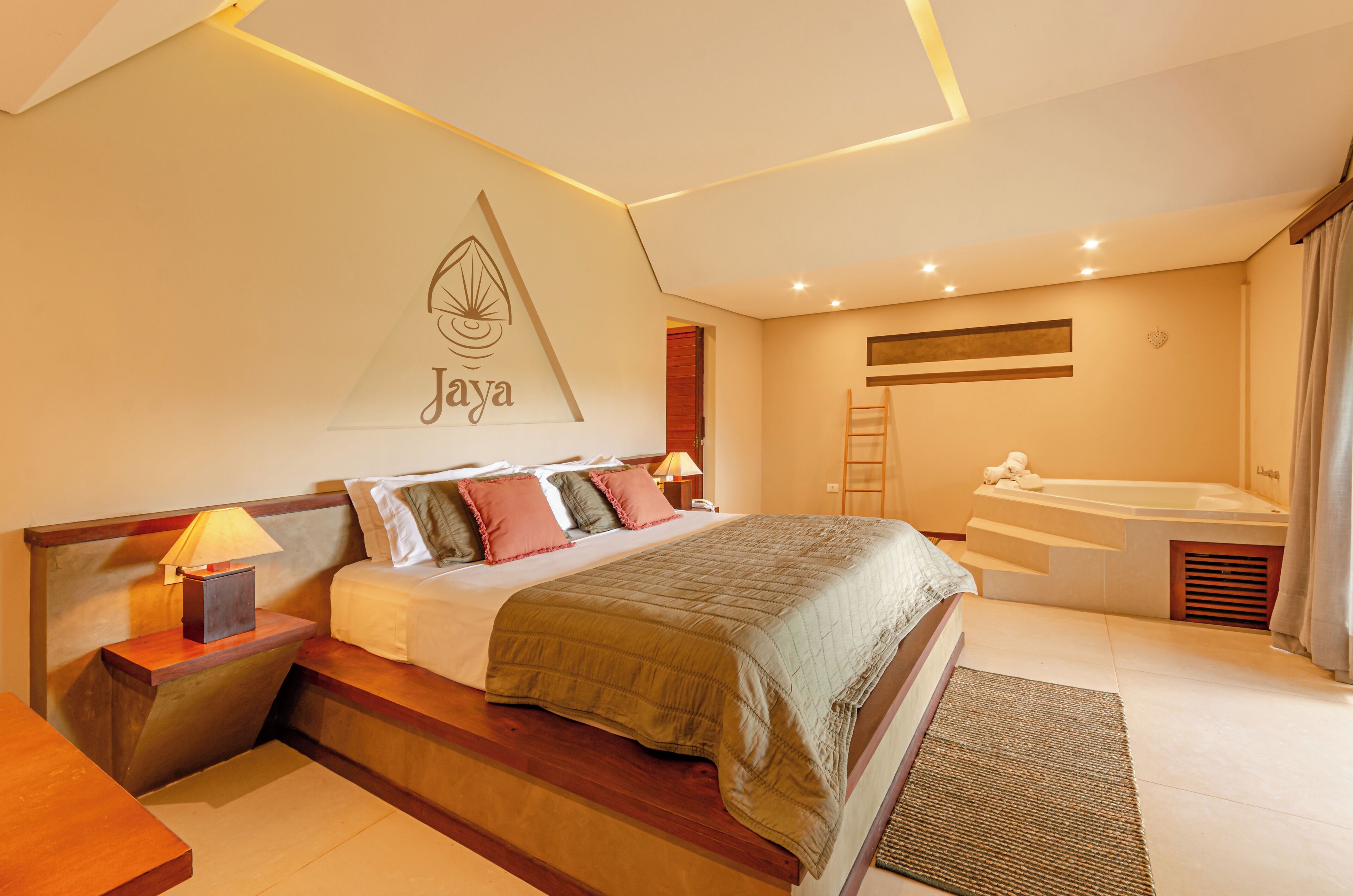 Habitación de hotel moderna con una cama grande, una mesita de noche con lámpara, un televisor montado en la pared y un baño con bañera y ducha.