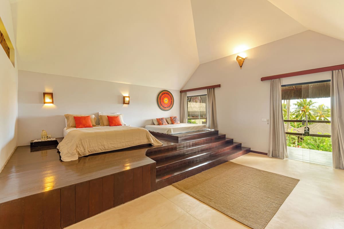 Quarto com duas camas, escada e varanda com cortinas.
