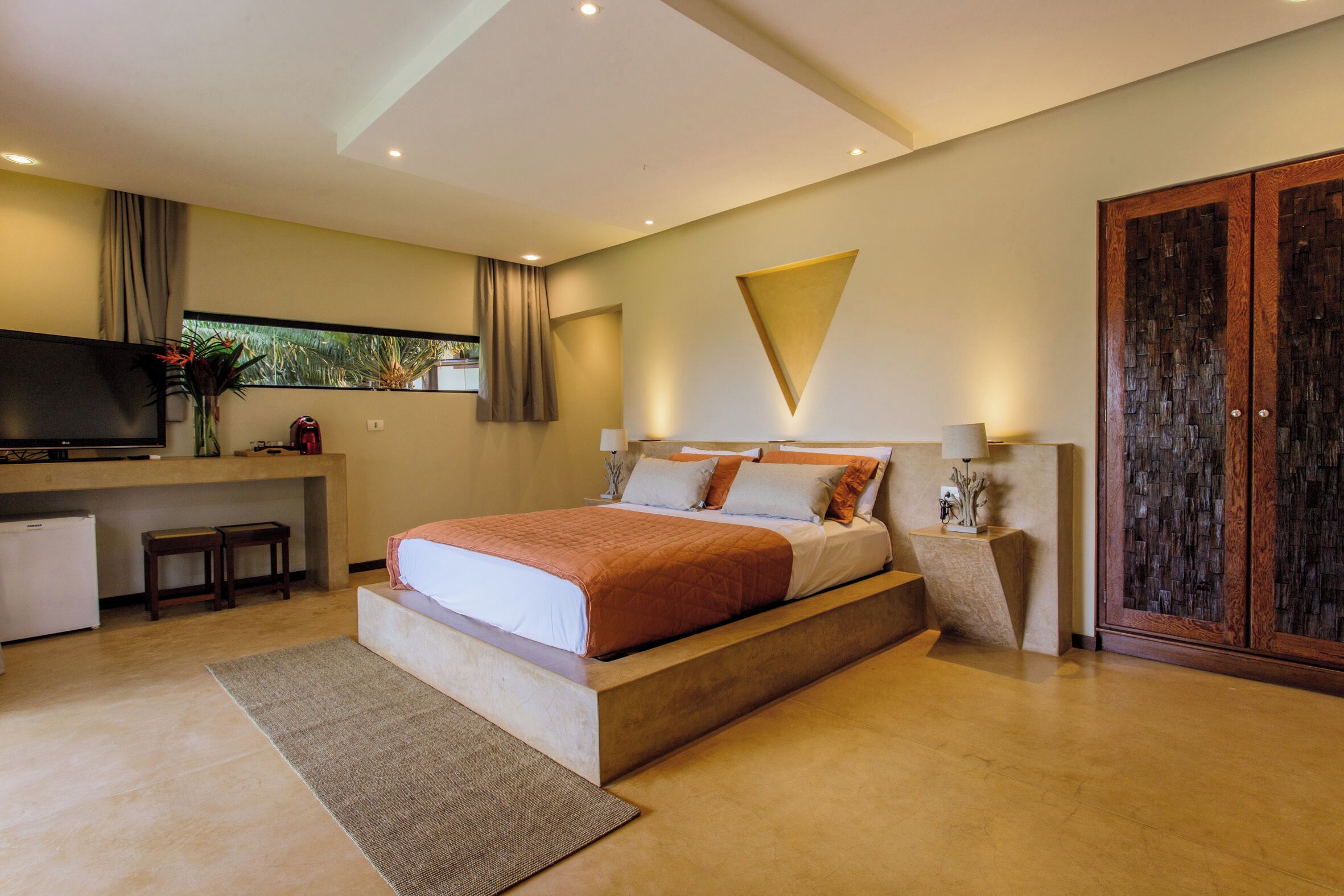 A modern bedroom with a bed, bedside tables, a TV, and a wardrobe.