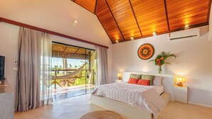 A spacious bedroom with a large bed, a hammock outside the window, and a view of palm trees. - Pousada Jaya Boutique (São Miguel do Gostoso)