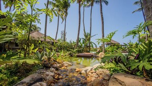 A tropical resort with a small stream, palm trees, and thatched-roof huts. - Pousada Jaya Boutique (São Miguel do Gostoso)