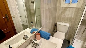Un bagno moderno con uno specchio grande, un lavabo bianco e un box doccia in vetro.