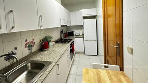 Una cucina con mobili bianchi, un piano di lavoro in granito, un lavello in acciaio inossidabile, un forno a microonde, un tostapane e un frigorifero.