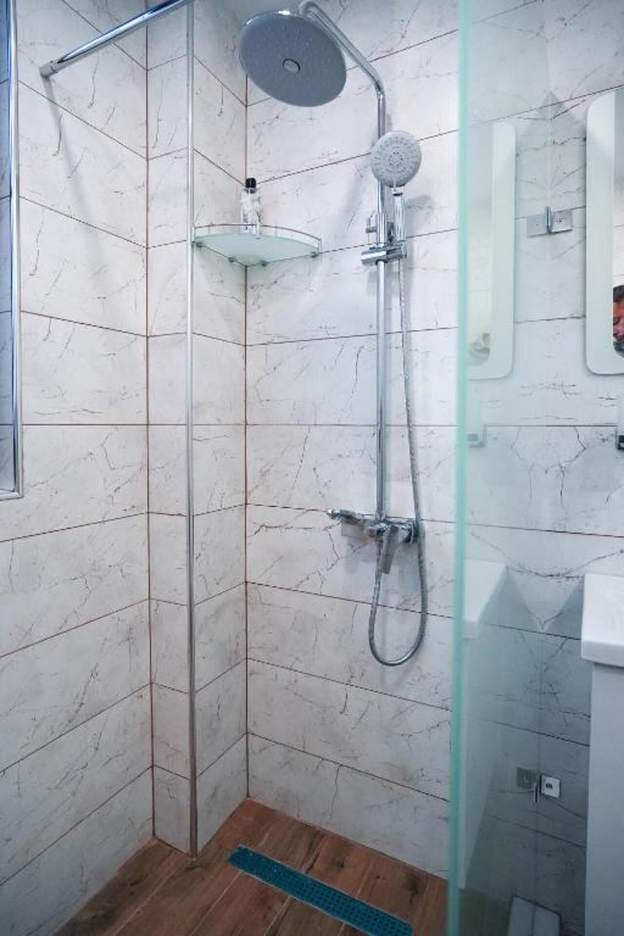 A shower with a glass enclosure, a handheld showerhead, and a wall-mounted faucet.