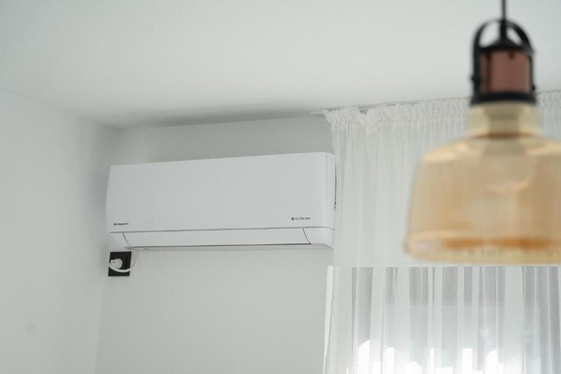 A white air conditioning unit mounted on a wall with a visible brand label.