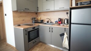 A compact kitchen with grey cabinets, a built-in oven, a sink, and a black refrigerator. - 2 Bed Apt - Sleeps 4, Terrace & Pet Friendly (Sandanski)