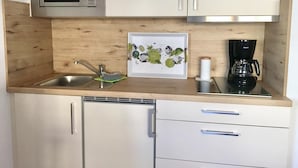 A compact kitchen with a microwave, sink, coffee maker, and a framed picture on the countertop. - House Nicole vacation apartment 1 (Cuxhaven)