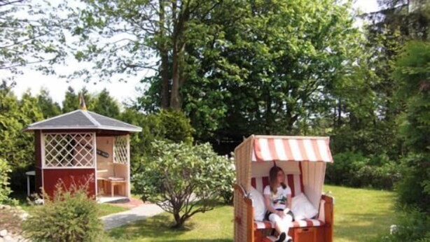 A garden with a small wooden structure and a striped canopy seating area. - House Nicole vacation apartment 3 (Cuxhaven)